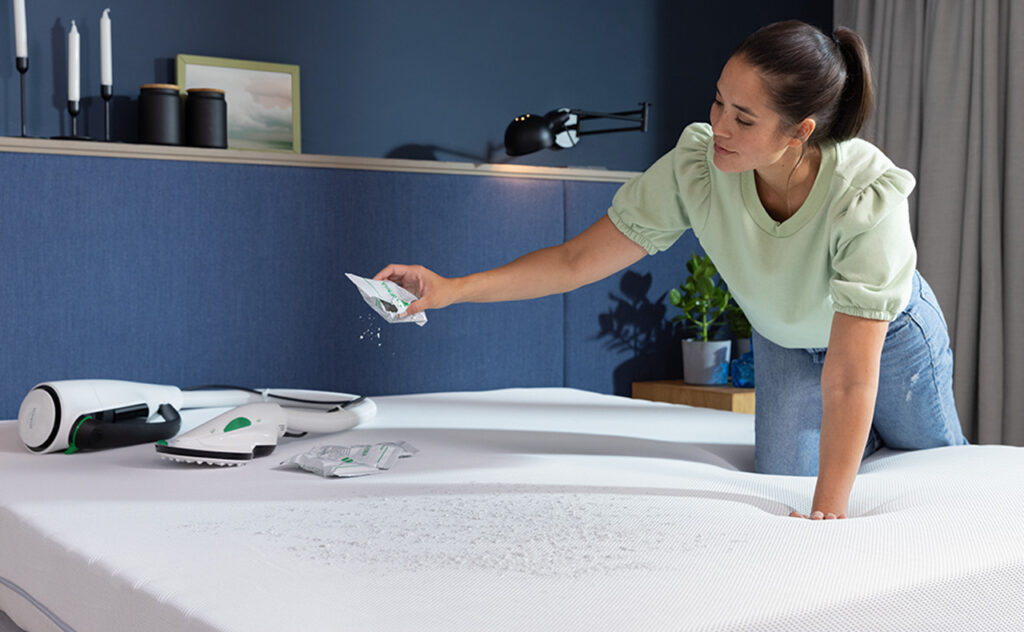 Woman uses Thermomix Kobold Vac mop attachment to clean mattress.