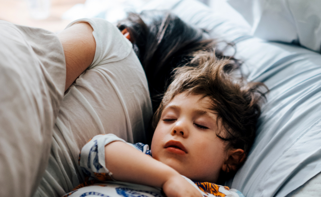 Mum sleeps with her back to a very comfy, fasl asleep toddler