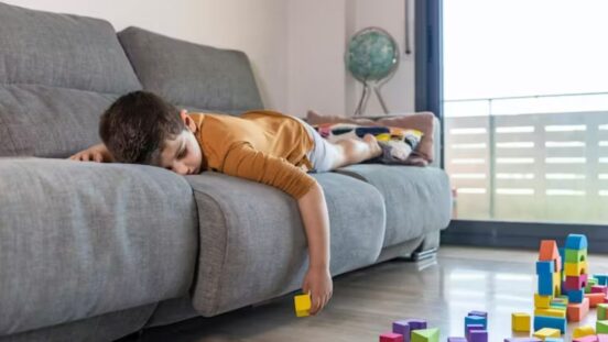 Boy laying on lounge looking bored with building blocks on the floor