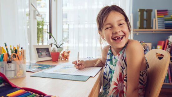 Young girl smiling while sitting at desk