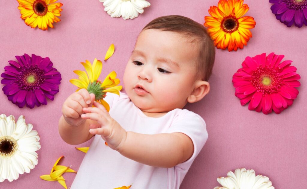 Spring baby names: Baby girl holding flower
