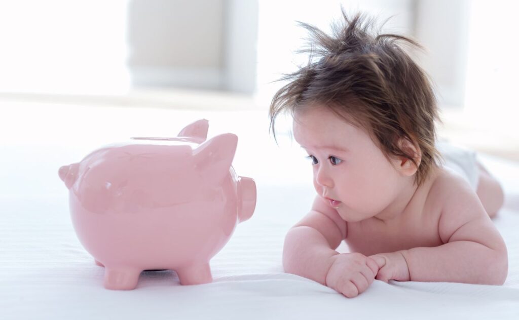 Wealthy baby names: baby boy looking at piggy bank