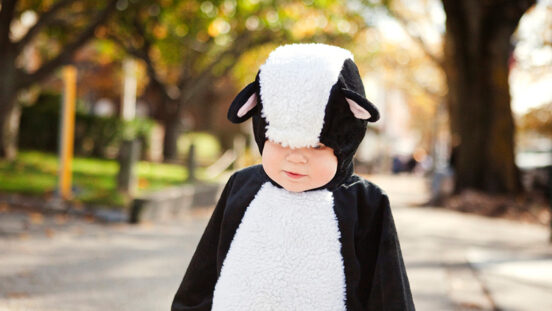 Baby boy in costume standing on footpath in NYC