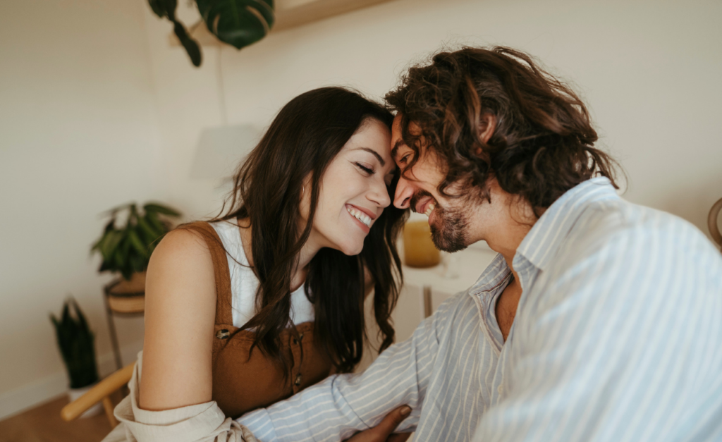 Young long-haired couple, smiling and leaning into each other so their foreheads touch