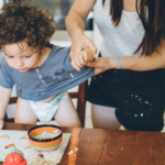 Curly haired toddler standing on dining chair