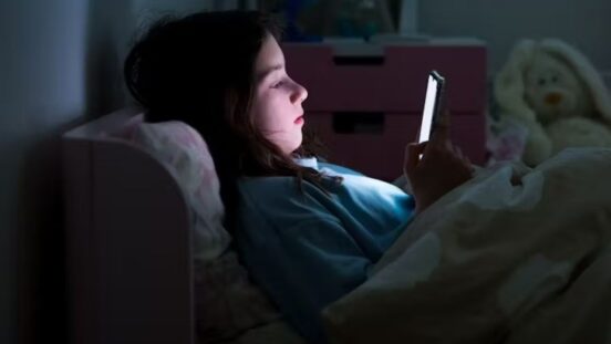 Girl lying in bed in the dark on her mobile phone