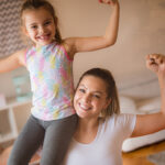 Just strong. Mother and daughter at home flexing their muscles