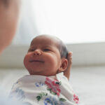 Father holding grinning newborn daughter