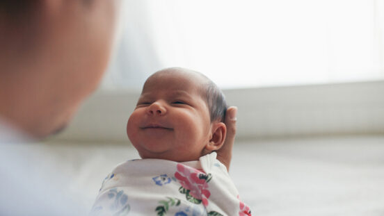 Father holding grinning newborn daughter