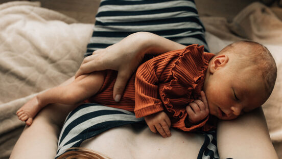 Close-up of a mother holding a newborn baby at home.