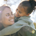 Smiling mum looks back at the daughter who is on her back