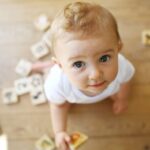 Baby playing with block and making eye contact.