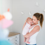 Mother and baby in nursery room with bird imagery on wall