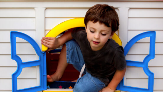 Boy plays and climbs through plastic window of toy cubby house.