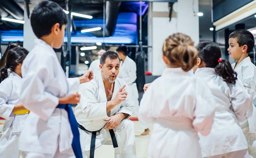 Very young students attend to the teacher during a karate lesson