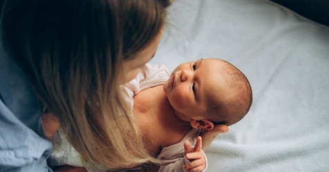 Mother making eye contact with alert newborn as she gets them dressed.