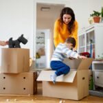 Mother smiling at toddler entering a box during packing for house move