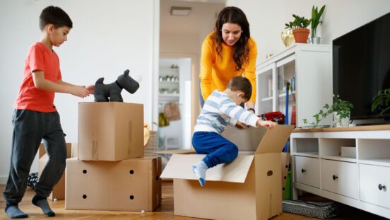 Mother smiling at toddler entering a box during packing for house move