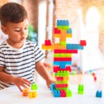 Beautiful toddler boy playing with construction blocks at kindergarten