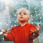 Rainy day things to do with toddler: Girl standing under umbrella