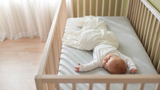 High angle view of baby boy sleeping in crib at home