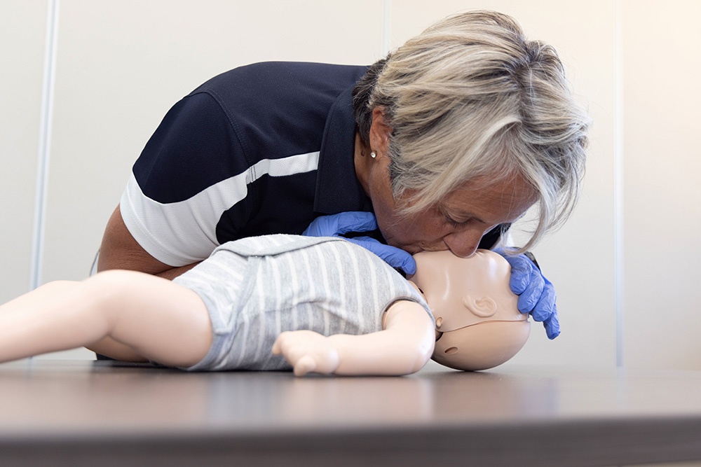 CPR instructor demonstrates baby CPR on model baby