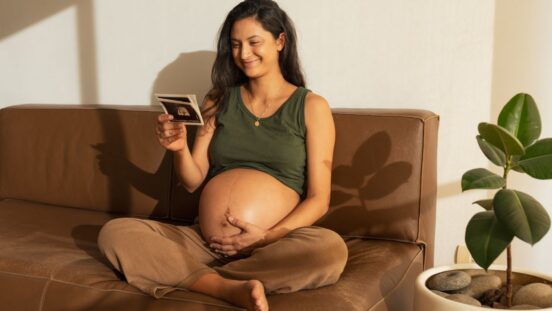 Happy pregnant woman looking at ultrasound scan at home