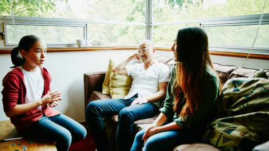 Father in discussion with daughters in living room