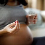 Pregnant woman taking pill at home