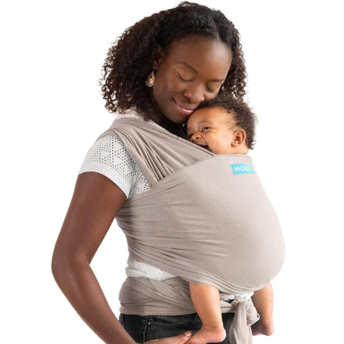 Dark-skinned mum carries smiling baby in taupe coloured Moby Elements Wrap Carrier
