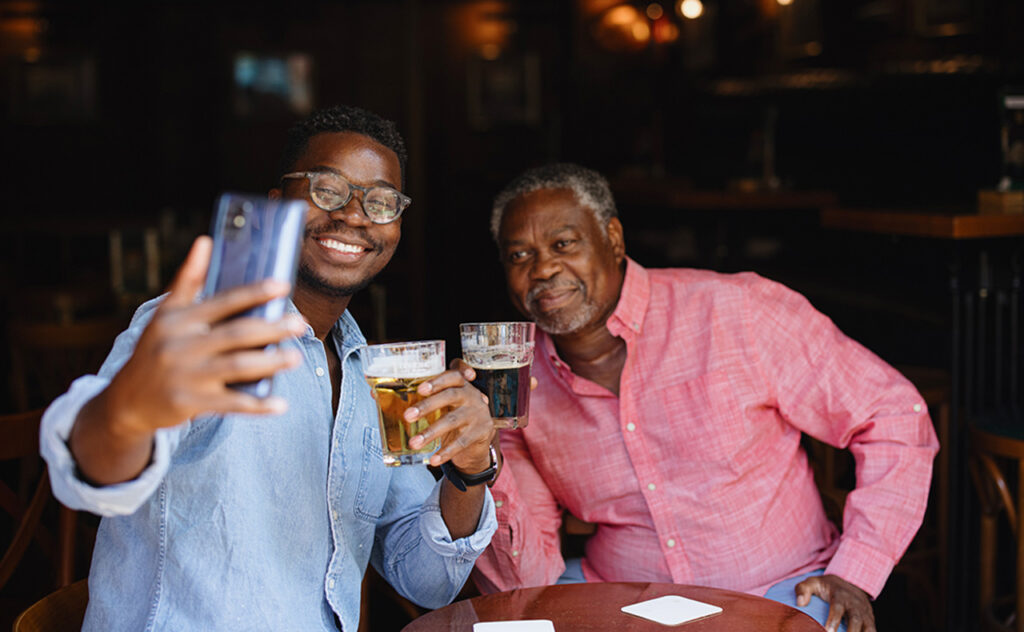 Father and adult son spending time together. Multi generation family. Two men drinking beer in the pub and having a chat