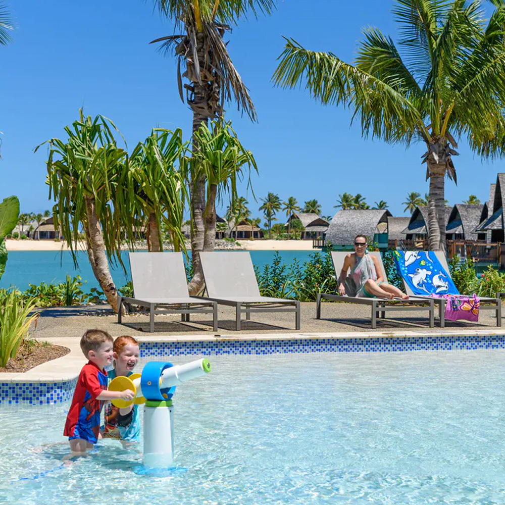 Two young brothers enjoy the pool at Fiji Marriott Resort Momi Bay while their mum looks on 