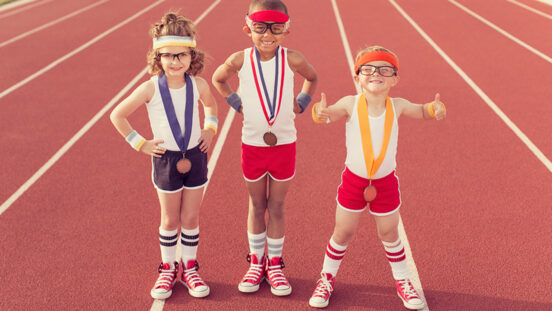 A group of three children dressed in vintage and retro workout attire are ready to show their running speed and agility on the track, albeit in a humorous way, winning medals along the way.