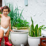 Adorable toddler boy outside in garden wearing Comfy Koala nappy and red gumboots
