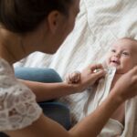 Mother dressing baby on bed
