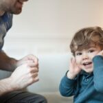Toddler looking at camera not listening to father