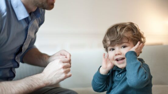 Toddler looking at camera not listening to father