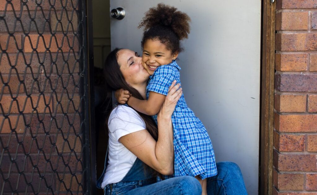 Mother kissing daughter on the cheek before school
