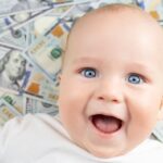 Rich baby names: Blue-eyed baby laying on dollar bills