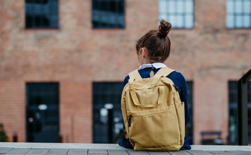 Back of Girl in school uniform with backpack