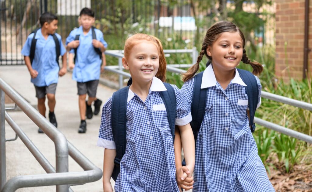 Make friends at school: Two school girls holding hands on way to school