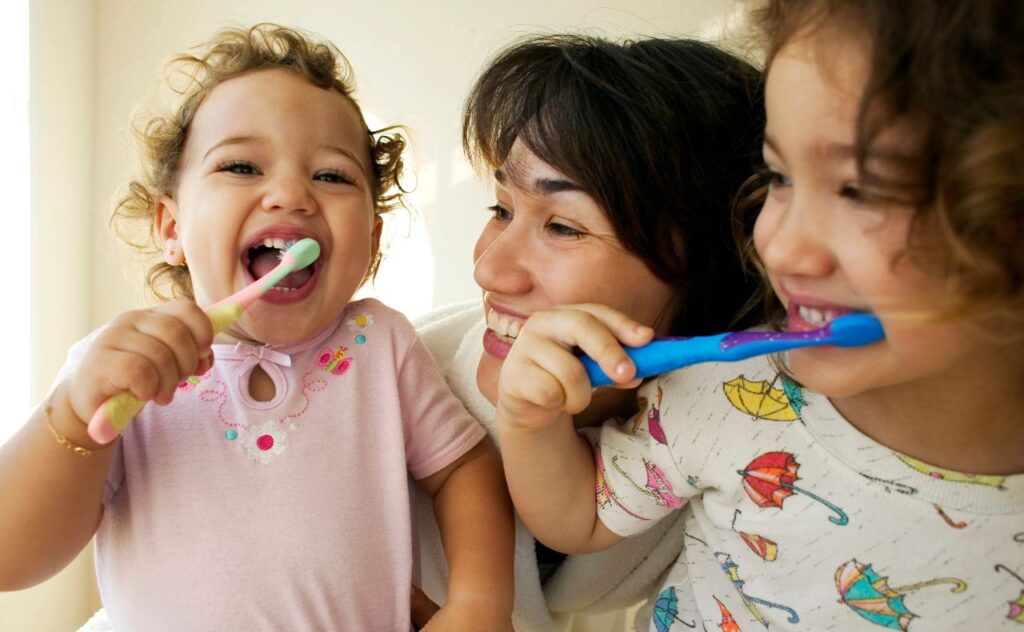 Mother Helping Daughters Brush Teeth