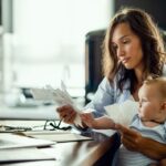 Smart money tips: Young mother with baby going through bills while analysing her home finances.