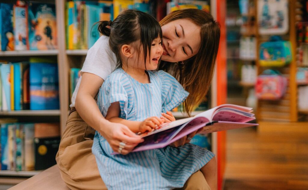 Young Asian mother reading story books to her little daughter