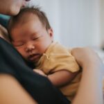 mother holding her newborn baby, while putting him to sleep