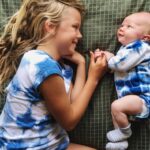 top baby names australia: Smiling baby lying down with older sibling