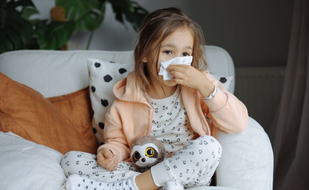 Allergies, asthma or a cold:  Toddler girl with tissue sitting at home on lounge