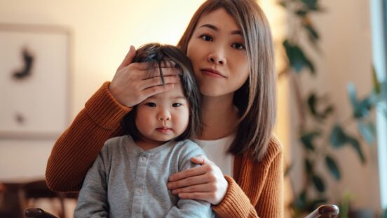 Cold and flu season: Expert tips. Asian mother with toddler who has a fever