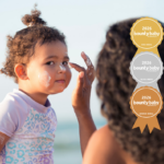 Mum applying suncreen to toddler daughter. The best sunscreen for keeping the whole family covered